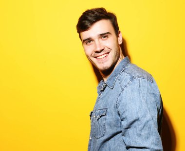 Sarı arka planda duran gülümseyen genç adamın portresi