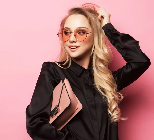 Hermosa mujer rubia en una blusa y pantalones con gafas, sosteniendo el bolso — Foto de Stock