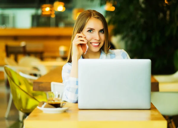 Image d'une femme heureuse utilisant un ordinateur portable et un smartphone dans un café. Le plus vivant — Photo