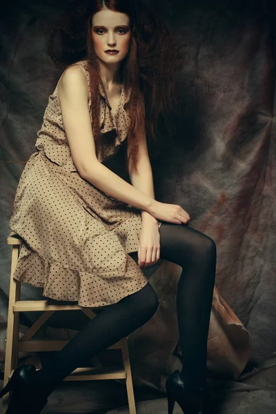 Jong mode model met creatieve make-up zitten op een kruk in — Stockfoto
