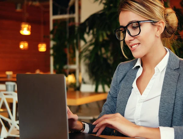 Una joven atractiva mujer de negocios sentada en un café con un lapto — Foto de Stock