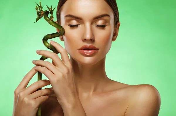 Young beautiful woman with bamboo over green background — Stock Photo, Image