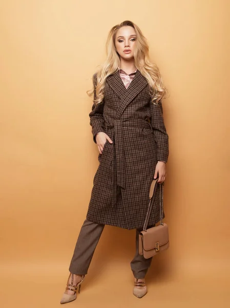 Móda, lidé a životní styl koncept: Krásná žena dlouhé blond kudrnaté vlasy oblečení kašmírový kabát a držení kabelky. — Stock fotografie