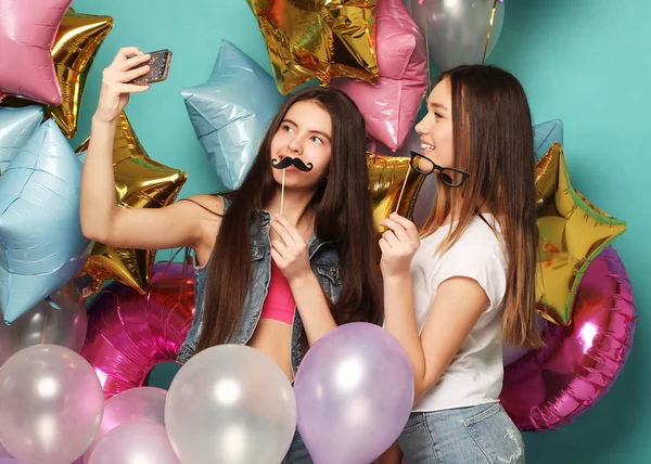 Renkli balonları olan iki kız arkadaş bir PH 'de selfie çekiyorlar. — Stok fotoğraf