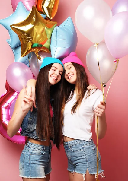 Two pretty emotional girls hold balloons and posing against pin — Stock Photo, Image