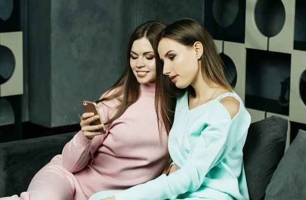 라이프 스타일과 사람 개념: 휴대 전화를 집에서 보고 하는 두 아름 다운 여자 — 스톡 사진