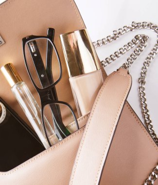 Kozmetik ürünler ve Acce ile açılmış pembe deri kadın çantası.