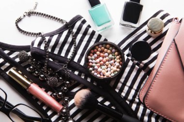 Kozmetik ürünleri, aksesuarlar ve beyaz arka planda akıllı telefonlu pembe deri kadın çantası.  