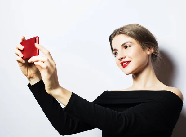 Känslor, uttryck och människor koncept - glada leende ung kvinna som bär svart klänning tar selfie med smartphone — Stockfoto