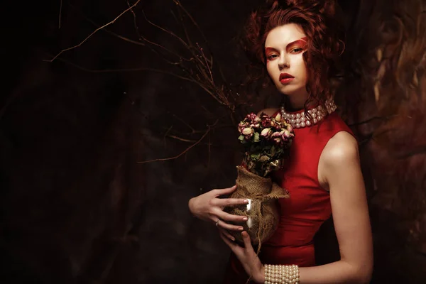Hermosa morena con estilo en vestido rojo sosteniendo un ramo de dri —  Fotos de Stock