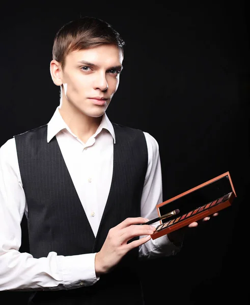 Young male make up artist holding shadow palette and brush. — Stock Photo, Image