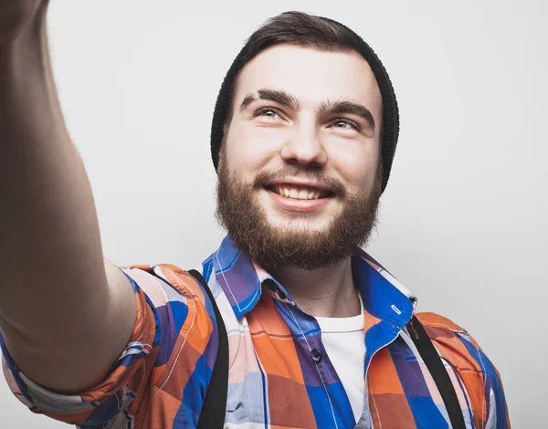 Close up portrait of a cheerful bearded man taking selfie over white background — Stock Photo, Image