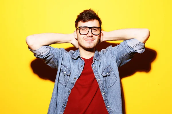 Portrait of young smiling man standing against yellow background — Stock Photo, Image