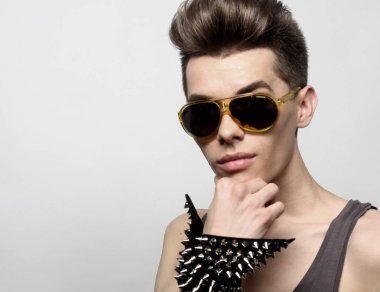 Moda tarzında güneş gözlüğü takan seksi genç adam. Erkek modeli. 