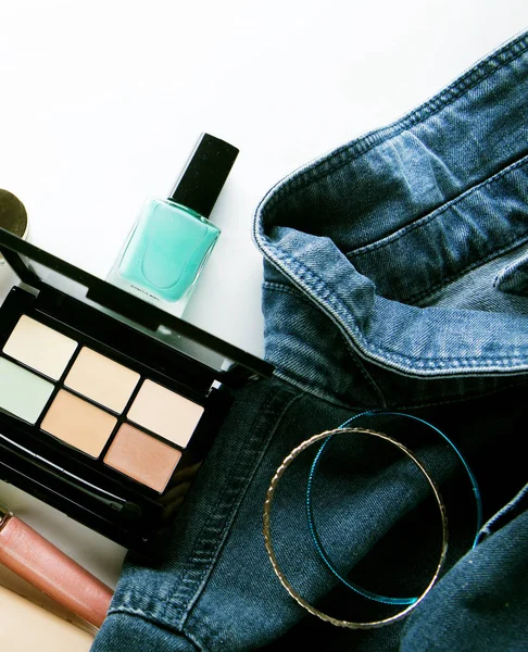 Bovenaanzicht van damesjeans shirt, concealer pallet, lipgloss, nagel — Stockfoto