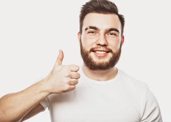 Portrét veselého mladého vousatého muže ukazující v pořádku gesto izolované na bílém pozadí — Stock fotografie
