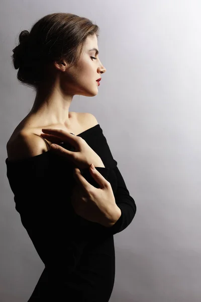 Mujer rubia en vestido negro posando con los brazos cruzados y mirando — Foto de Stock