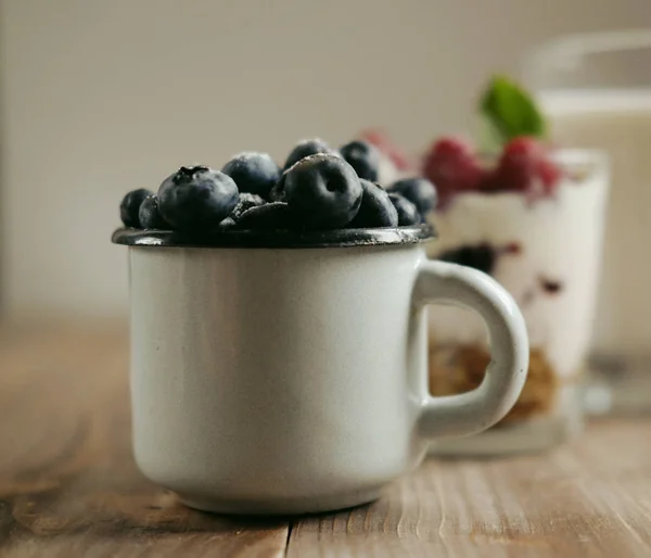 Fröhliches Frühstück. ein kleiner Becher mit Blaubeeren, ein Glas Milch und — Stockfoto