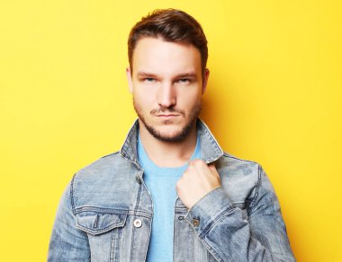 Yakışıklı bir genç adam, manken portresi. Sarı duvardan poz.