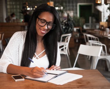 Yaşam tarzı ve insan konsepti: Güzel Afrikalı kız kafeteryada notlar alıyor