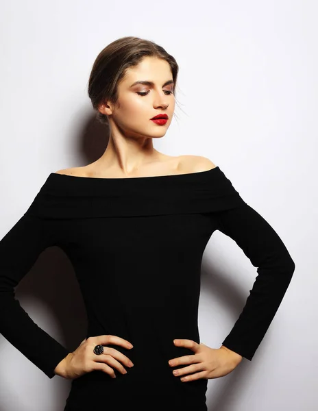 Ung vacker kvinna som bär svart klänning poserar över vit bakgrund — Stockfoto