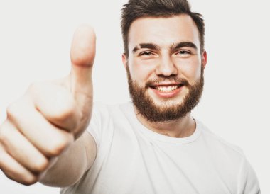 Beyaz arka planda izole edilmiş iyi bir hareket gösteren neşeli, sakallı genç bir adamın portresi.