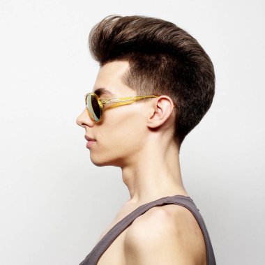 Beyaz bir arka plan üzerinde güneş gözlüklü genç adam. Moda kavramı. Stüdyo çekimi.