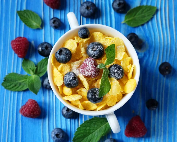 Healthy eating, food and diet concept - Cornflakes with berries raspberries and blueberries on blue wooden background. Top view. — Stock Photo, Image