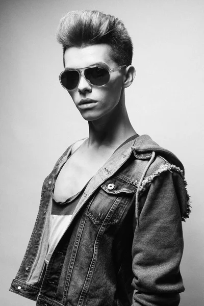 Handsome young man model with fashion haircut and sunglasses posing in studio. Black and white picture. — Stock Photo, Image