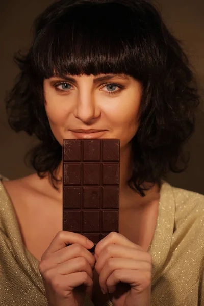 Schönes Mädchen mit Schokolade auf beigem Hintergrund — Stockfoto