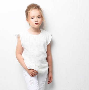 Beyaz arka planda beyaz giysili güzel bir moda kızı. Çocuk modası..