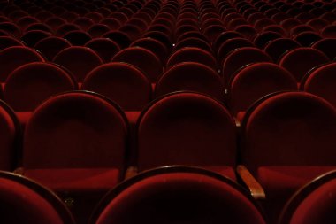 Kırmızı kadifeli numaralandırılmış tiyatro sandalyeleri.