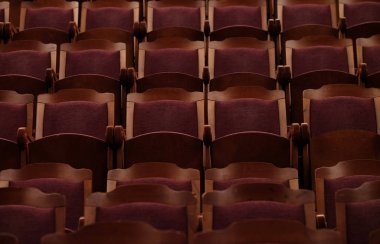 Kırmızı kadifeli numaralandırılmış tiyatro sandalyeleri.