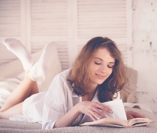 美丽的金发女人在床上看书。放松的概念 — 图库照片