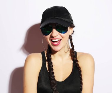 Bir kap ve beyaz arka plan üzerinde güneş gözlüğü genç bir kadın portresi. Sportif tarzı