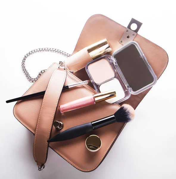 Flat lay de couro rosa mulher saco aberto com cosméticos, acessórios e smartphones no fundo branco — Fotografia de Stock