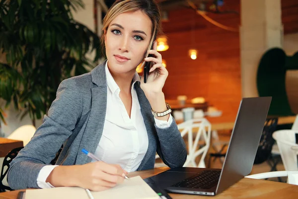 Mujer feliz usando el chat con el móvil y el ordenador portátil de uso y trabajando en el restaurante cafetería, estilo de vida de la era digital, Trabajar fuera del concepto de oficina. — Foto de Stock