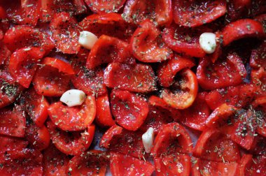 Domatesler fırın tepsisine konmuş, pişirmeye hazır. Sarımsaklı güneşte kurutulmuş domates. Gıda arkaplanı.