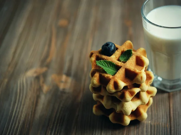 Вафлі та склянка з молоком. Ранковий сніданок на дерев'яному фоні . — стокове фото