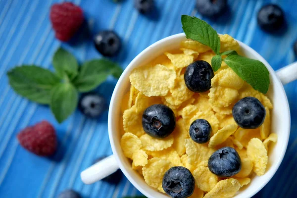 Healthy eating, food and diet concept - Cornflakes with berries raspberries and blueberries on blue wooden background. Top view. — Stock Photo, Image