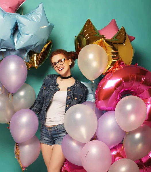 Porträt eines glücklichen Rothaarmädchens, das auf Party wartet. wunderschöne fröhliche junge Frau, die Spaß mit funkelnden Luftballons hat, vor blauem Hintergrund. — Stockfoto