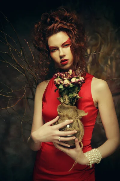 Linda morena elegante em vestido vermelho segurando um buquê de flores secas — Fotografia de Stock