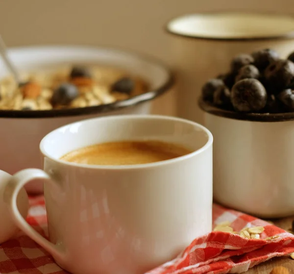 Um café da manhã saudável é um ótimo começo para um novo dia. Mingau de aveia, café, bagas e nozes em uma mesa de madeira . — Fotografia de Stock
