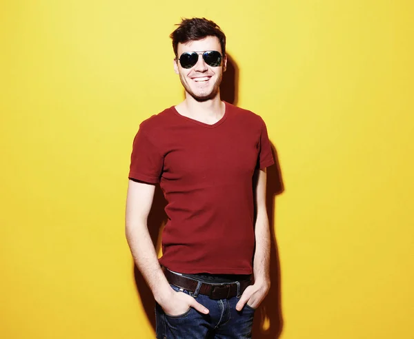 Porträtt av en ung man som bär solglasögon på gul bakgrund — Stockfoto