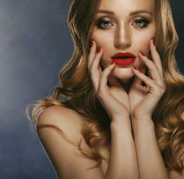 Uzun kıvırcık saç ve kırmızı dudaklar ile güzel kız. Kırmızı manikür çivi üzerinde. Güzellik ve estetik bakım. Koyu arka plan.