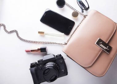 Beyaz arka plan üzerinde kadın bej çanta aksesuarları smartphone, kozmetik, lasses, kamera ve parfüm ile Üstten Görünüm.