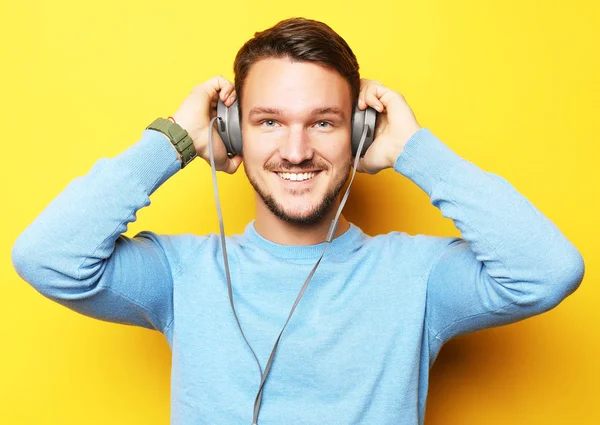 生活方式和人的概念：快乐的年轻人在黄色背景下听着带耳机的音乐 — 图库照片