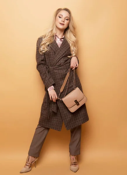 Móda, lidé a životní styl koncept: Krásná žena dlouhé blond kudrnaté vlasy oblečení kašmírový kabát a držení kabelky. — Stock fotografie