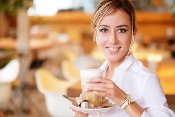 Uśmiechnięta kobieta w dobrym nastroju z filiżanką kawy siedzącej w kawiarni. — Zdjęcie stockowe