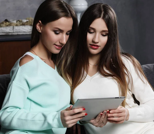 Deux belles jeunes femmes se détendre sur le plancher du salon en regardant un ordinateur portable et en riant de quelque chose à l'écran . — Photo